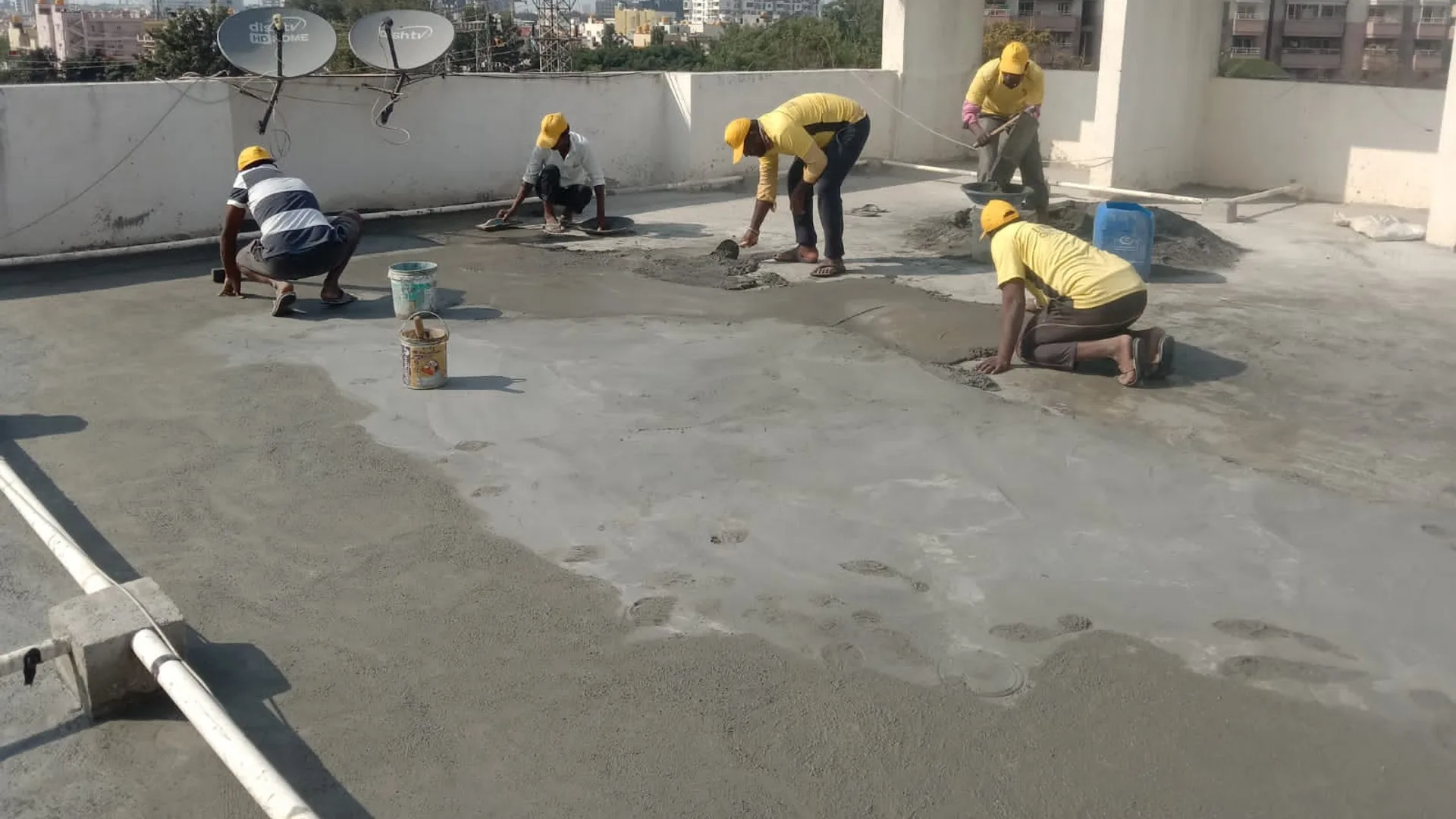 An Ultra Max crew troweling a fresh waterproofing coat across a Bangalore terrace