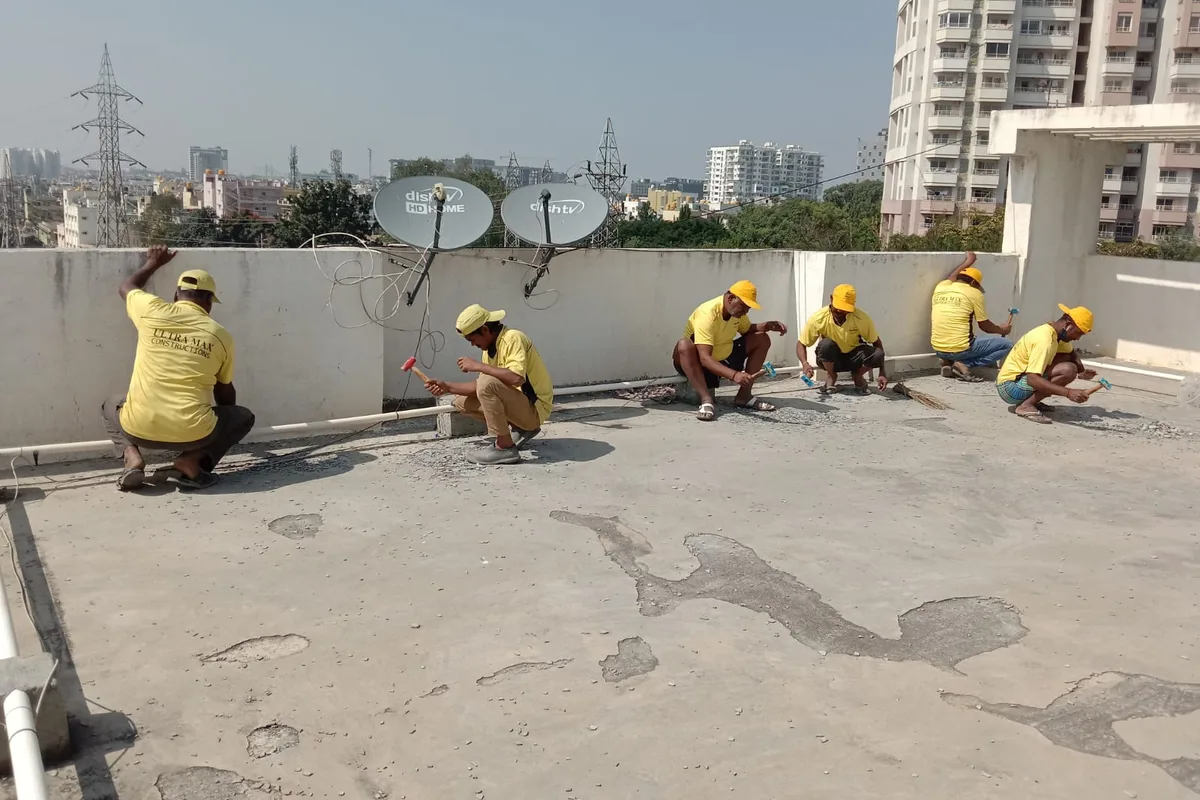 Ultra Max technicians working material into the junction between terrace floor and parapet by hand